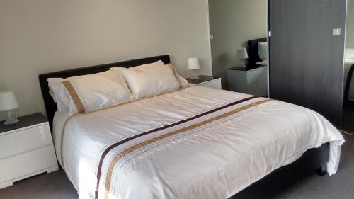 a bedroom with a large bed with white sheets and pillows at Camberwell Vacation Apartment in Melbourne