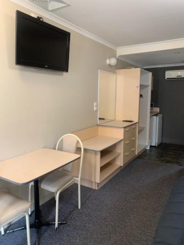 a room with a desk and a tv on the wall at Mid Coast Motor Inn in Macksville