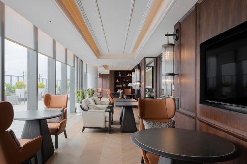 a hotel lobby with tables and chairs and a tv at 汕头白天鹅酒店 in Batou