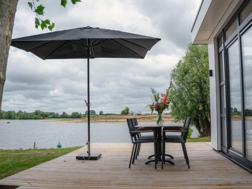 a table and chairs with an umbrella on a deck at House in Arnhem with Rhine Views in Maurik