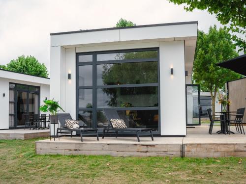a house with glass doors and benches on a patio at House in Arnhem with Rhine Views in Maurik