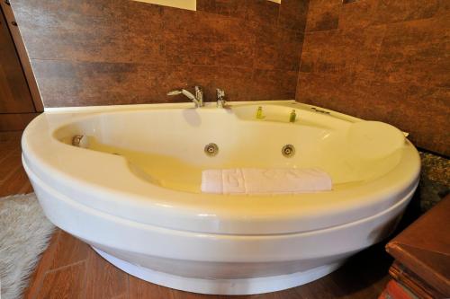 a white bath tub in a bathroom with brown tiles at Guesthouse Nifada tou Vorra in Palaios Agios Athanasios