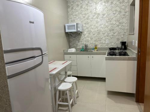 a kitchen with white cabinets and a refrigerator at Novíssimo apt 1 quarto Centro frente à Prefeitura in Nova Friburgo