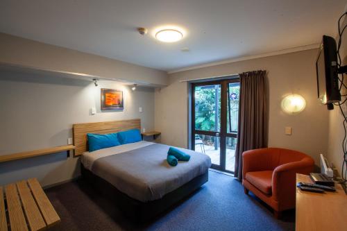 a hotel room with a bed and a chair at Ivorytowers Accommodation in Fox Glacier