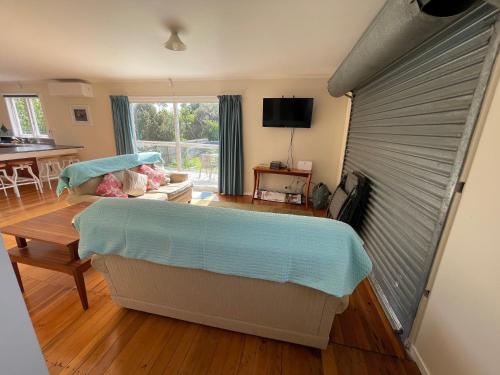 a room with a bed and a table and a window at Relaxing Raglan & the Boat House in Raglan