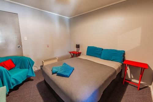 a bedroom with a bed with blue and red pillows on it at Ivorytowers Accommodation in Fox Glacier