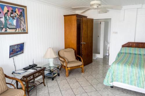 a bedroom with a bed and a chair and a table at Cleopatra Villas - Sea View in Rodney Bay Village