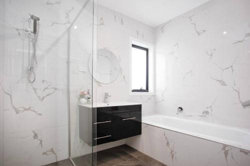 a bathroom with a shower and a tub and a sink at Brand New Delight Home at Throsby with 4 Bedrooms in Harrison