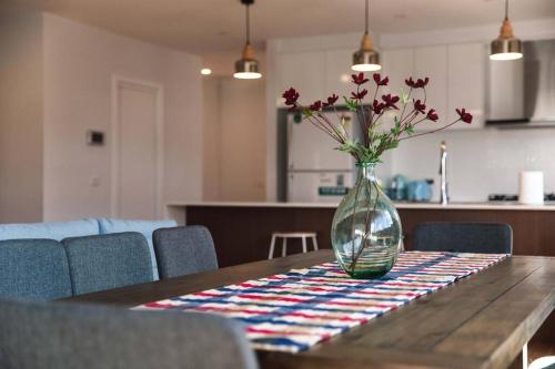 a vase with flowers sitting on a wooden table at Brand New Delight Home at Throsby with 4 Bedrooms in Harrison