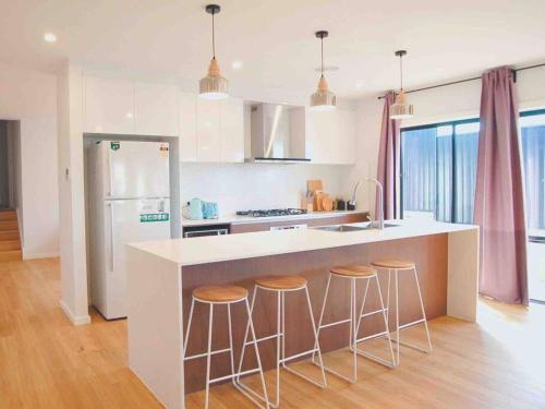 a kitchen with a island with bar stools and a refrigerator at Brand New Delight Home at Throsby with 4 Bedrooms in Harrison