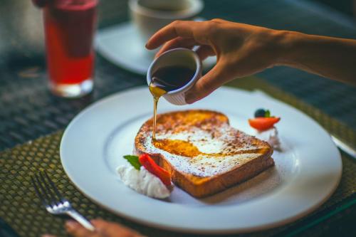 a person is pouring syrup onto a plate of toast at Jungle Vista Boutique Hotel in Manuel Antonio