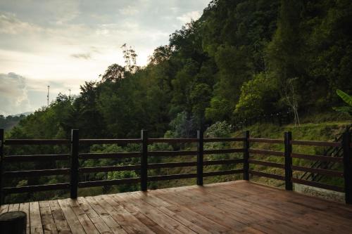 a wooden deck with a fence in front of a hill at Refined cabin, panoramic views, steps from Jericó in Jericó