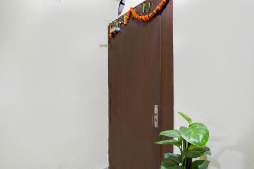 a door with a garland on it next to a plant at Hotel O Malviya Nagar Inn in New Delhi
