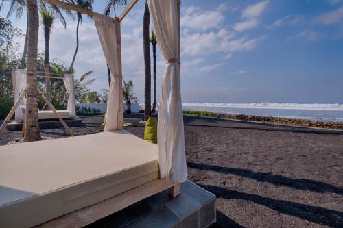 a bed on a beach with the ocean in the background at Saba Villa by Sanga Sanga Hospitality in Saba