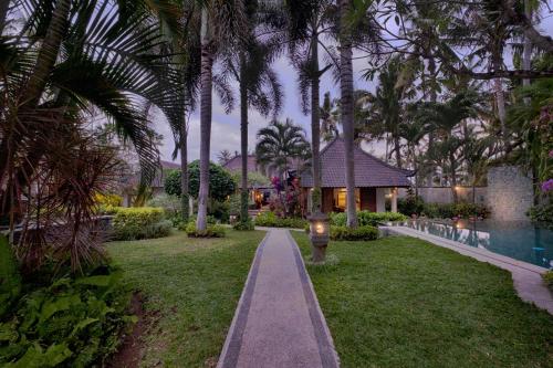 a garden with palm trees and a house at Saba Villa by Sanga Sanga Hospitality in Saba
