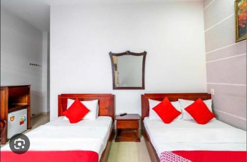 two beds in a room with red pillows at My Trà Hotel in Nam Ðịnh