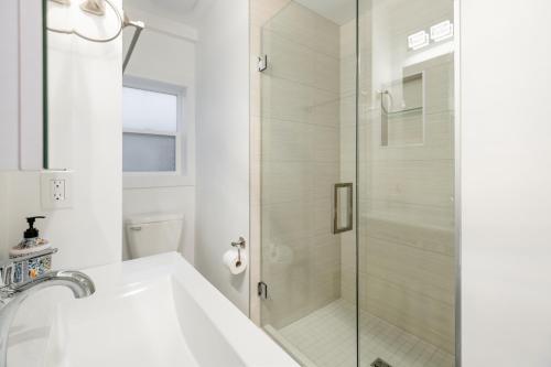 a white bathroom with a shower and a sink at Vancouver Central Green Studio in Vancouver