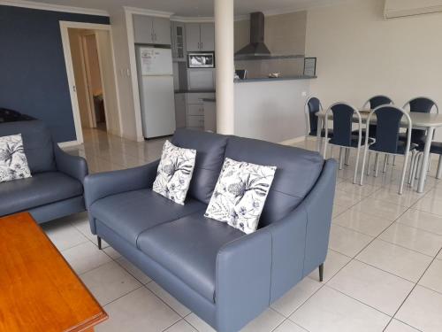 a blue couch in a living room with a kitchen at Ambience Apartments 1 in Coffin Bay