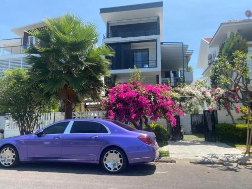 a purple car parked in front of a house with pink flowers at M Villa Nha Trang in Nha Trang