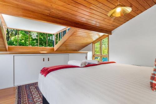 a bedroom with a large white bed with a wooden ceiling at On Village Green in Arrowtown