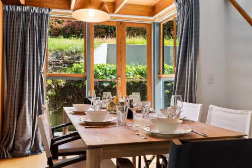 a wooden table with glasses and plates on it in front of a window at On Village Green in Arrowtown