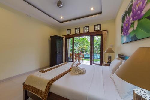 a bedroom with a large bed and a window at The Tunjung Ubud Retreat in Ubud