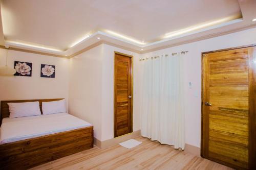 a small bedroom with a bed and a wooden door at Durhan White Beach Resort powered by Cocotel in Tabuelan