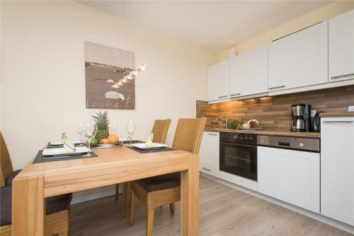 a kitchen with a wooden table and white cabinets at Tunghoern-Hues-1OG-Wohnung-04 in Keitum