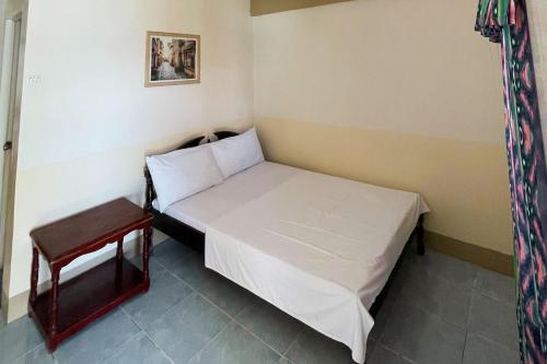 a small bedroom with a white bed and a stool at Durhan White Beach Resort powered by Cocotel in Tabuelan