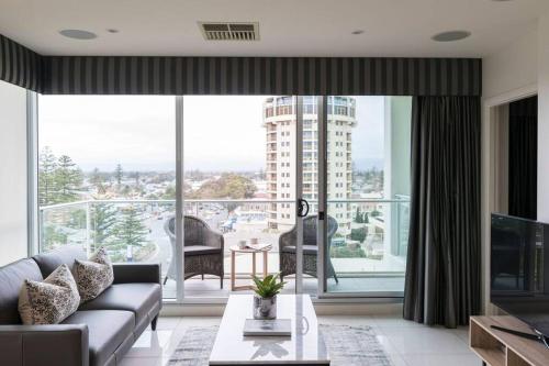 a living room with a couch and a large window at Liberty 727 -Glenelg- Marina & City Views in Glenelg