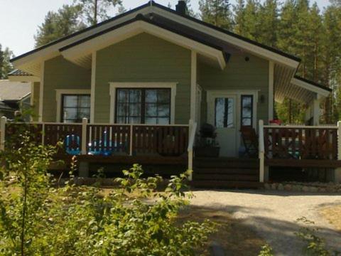 una pequeña casa verde con porche y terraza en Villa Paradise at Puruvesi Saimaa en Punkaharju