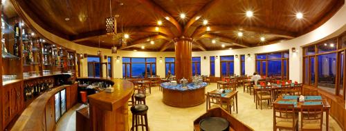 Un restaurante con mesas y sillas en una habitación con ventanas. en Rupakot Resort, en Pokhara