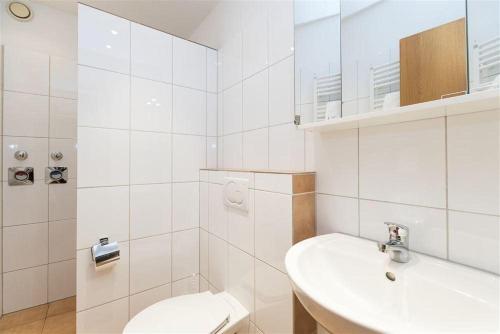 une salle de bains blanche avec toilettes et lavabo dans l'établissement Haus-Ornum-1-OG-O-Wohnung-13, à Westerland