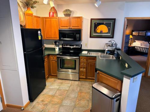 a kitchen with a black refrigerator and a sink at Ski-In Ski-Out Condo at Zephyr Mountain Lodge 1518 in Winter Park