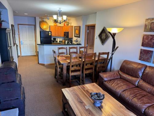 a living room with a table and a leather couch at Ski-In Ski-Out Condo at Zephyr Mountain Lodge 1518 in Winter Park