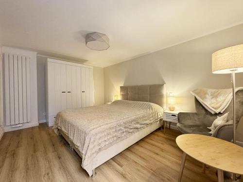 Un dormitorio con una cama, una silla y una mesa. en Haus-Excelsior-Wohnung-08, en Rantum