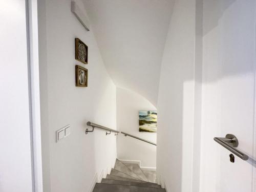 una escalera en una casa con paredes blancas y barandilla en Haus-Excelsior-Wohnung-08, en Rantum