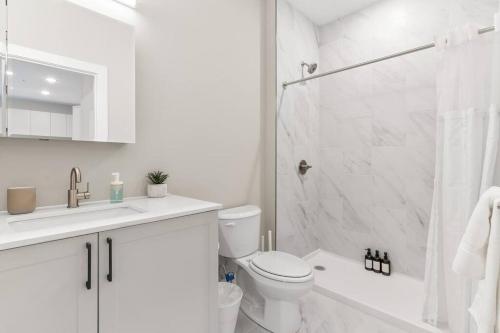 a white bathroom with a toilet and a shower at Modern 1-BD - Pier Views - Near Old City in Philadelphia