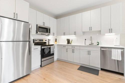 a kitchen with white cabinets and a stainless steel refrigerator at Modern 1-BD - Pier Views - Near Old City in Philadelphia