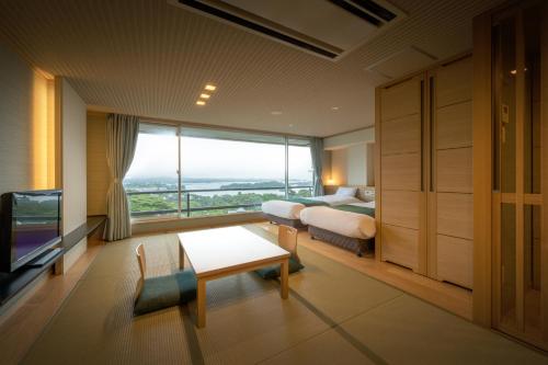a bedroom with a bed and a large window at Hotel Matsushima Taikanso in Matsushima