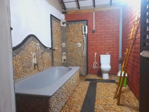 une salle de bain avec baignoire et toilettes dans l'établissement Sandalwood Family Cottages, à Uda Walawe