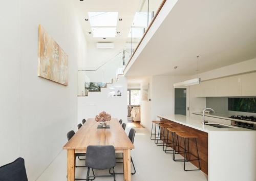 a kitchen and dining room with a wooden table and chairs at Swanston Sands - Sophisticated Comfort by the Beach in Geelong