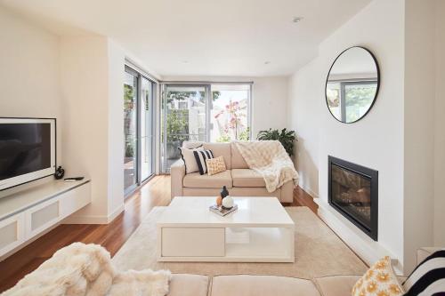 a living room with a couch and a tv at Swanston Sands - Sophisticated Comfort by the Beach in Geelong