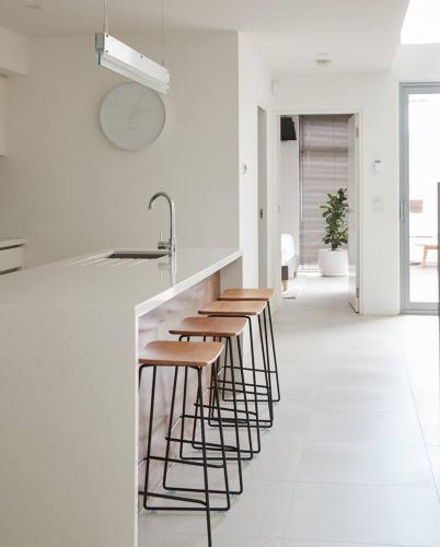 a row of stools in a kitchen with a counter at Swanston Sands - Sophisticated Comfort by the Beach in Geelong