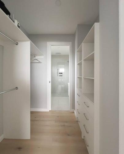 an empty room with white cabinets and a hallway at Harbour Horizons - Balcony BBQs and Calm Water Views in Clifton Springs