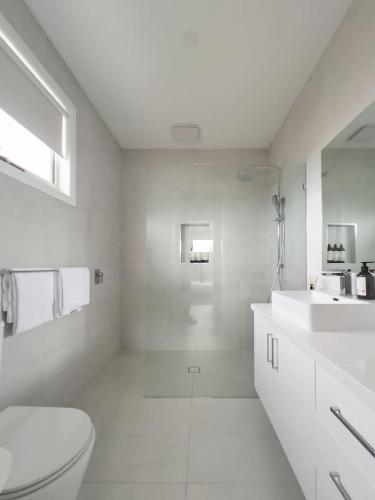 a white bathroom with a toilet and a sink at Harbour Horizons - Balcony BBQs and Calm Water Views in Clifton Springs