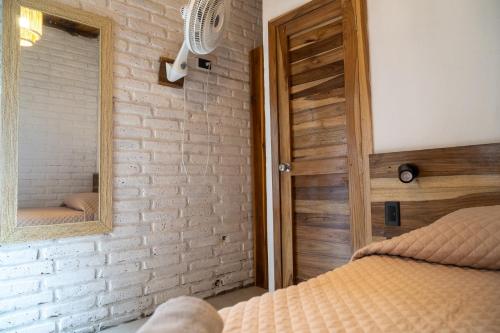 a bedroom with a brick wall and a mirror at Las Golondrinas Ayampe in Ayampe