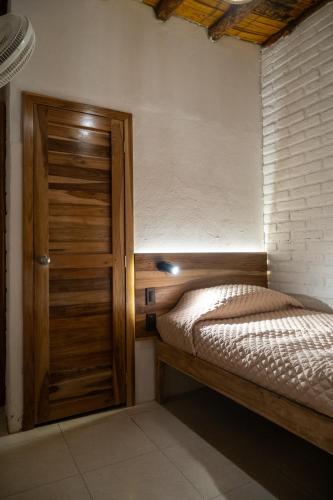 a small bedroom with a bed and a wooden door at Las Golondrinas Ayampe in Ayampe