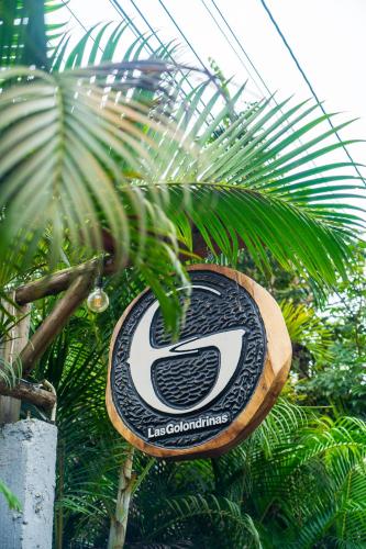 a sign in front of a palm tree at Las Golondrinas Ayampe in Ayampe