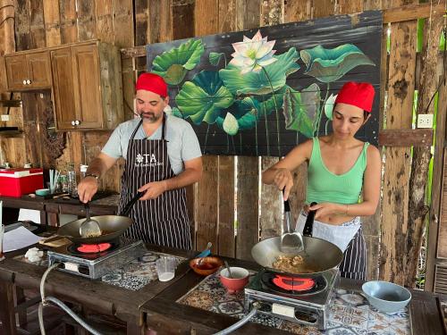a man and a woman preparing food in a kitchen at Ta Thai Cooking & Stay in Ban Khlong Tan